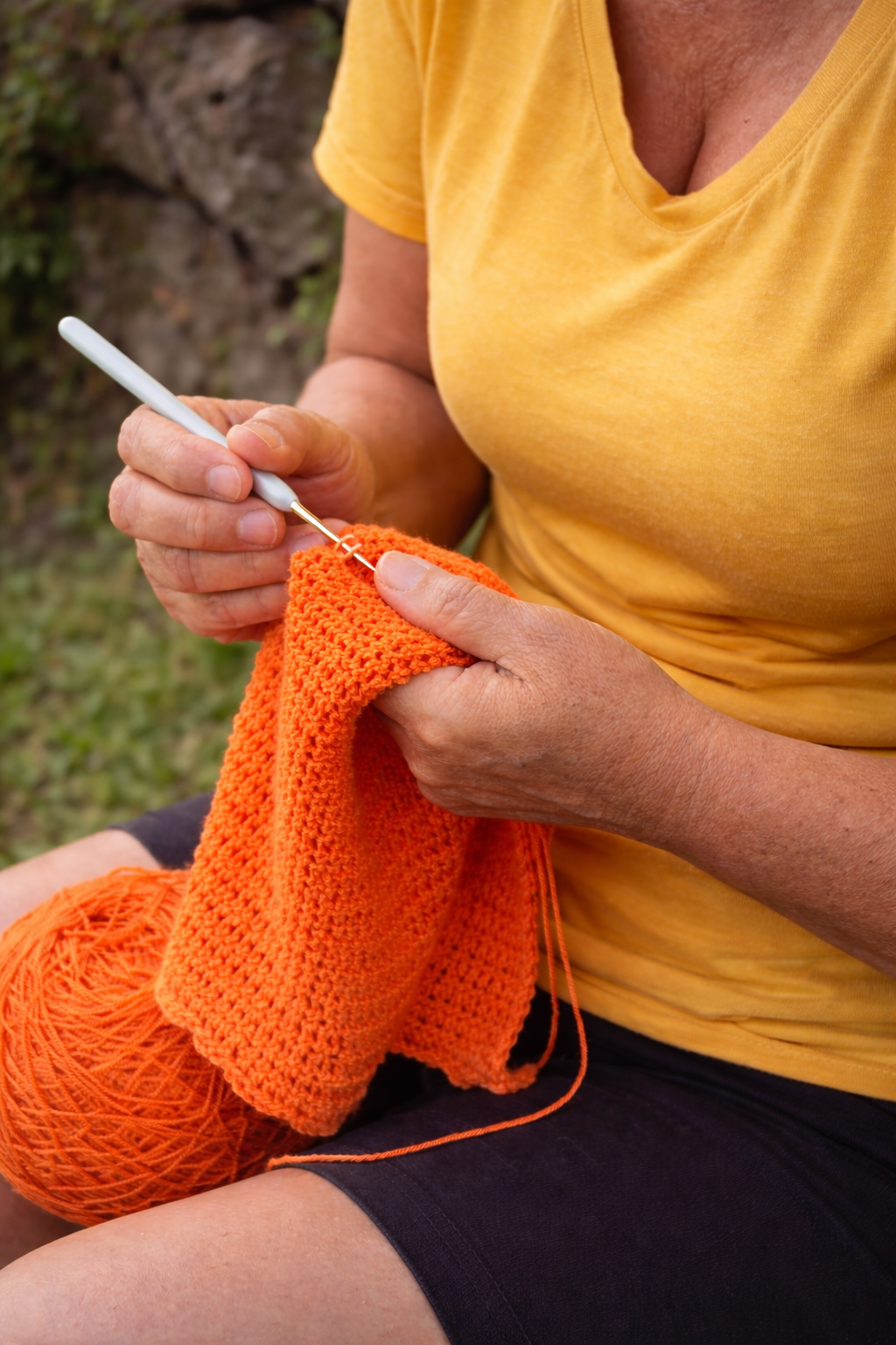 Mãos de artesã trabalhando crochê com fio e agulha